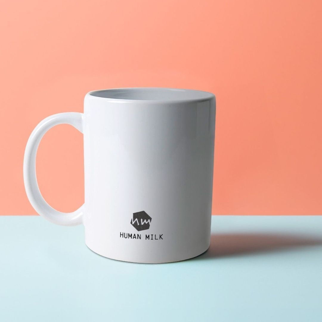 A white mug with a Human Milk logo in black