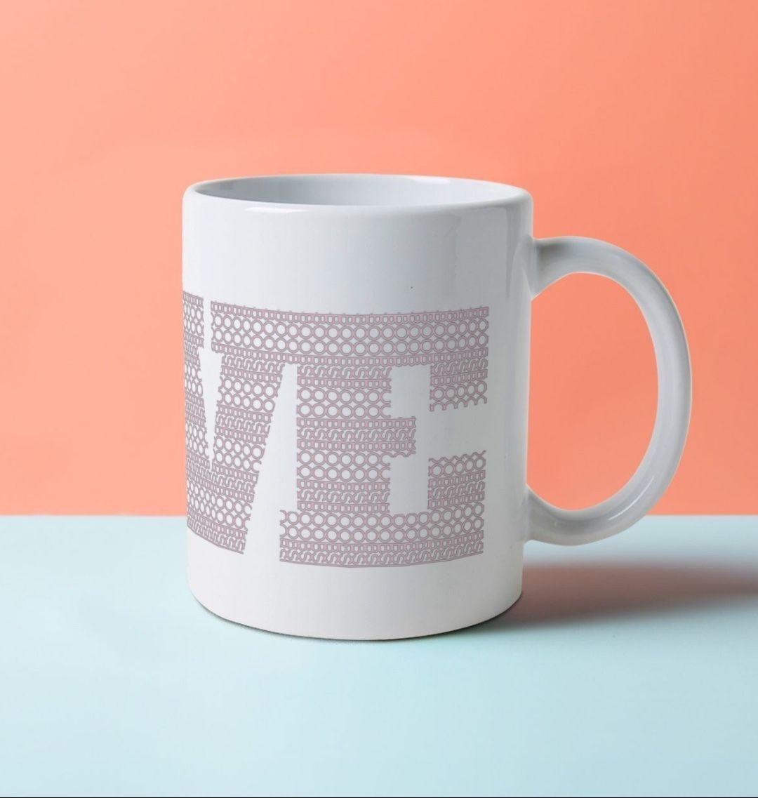 A white ceramic mug with the word LOVE on it, composed of a pattern made with the word BOOB.