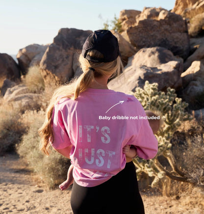 Person wearing a pink sweatshirt with text in a desert setting