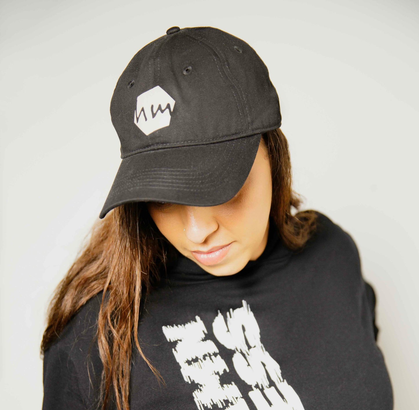 Woman wearing a black Human milk cap and black Human Milk hoodie with Goddamn Goddess written dow the side, against a plain background