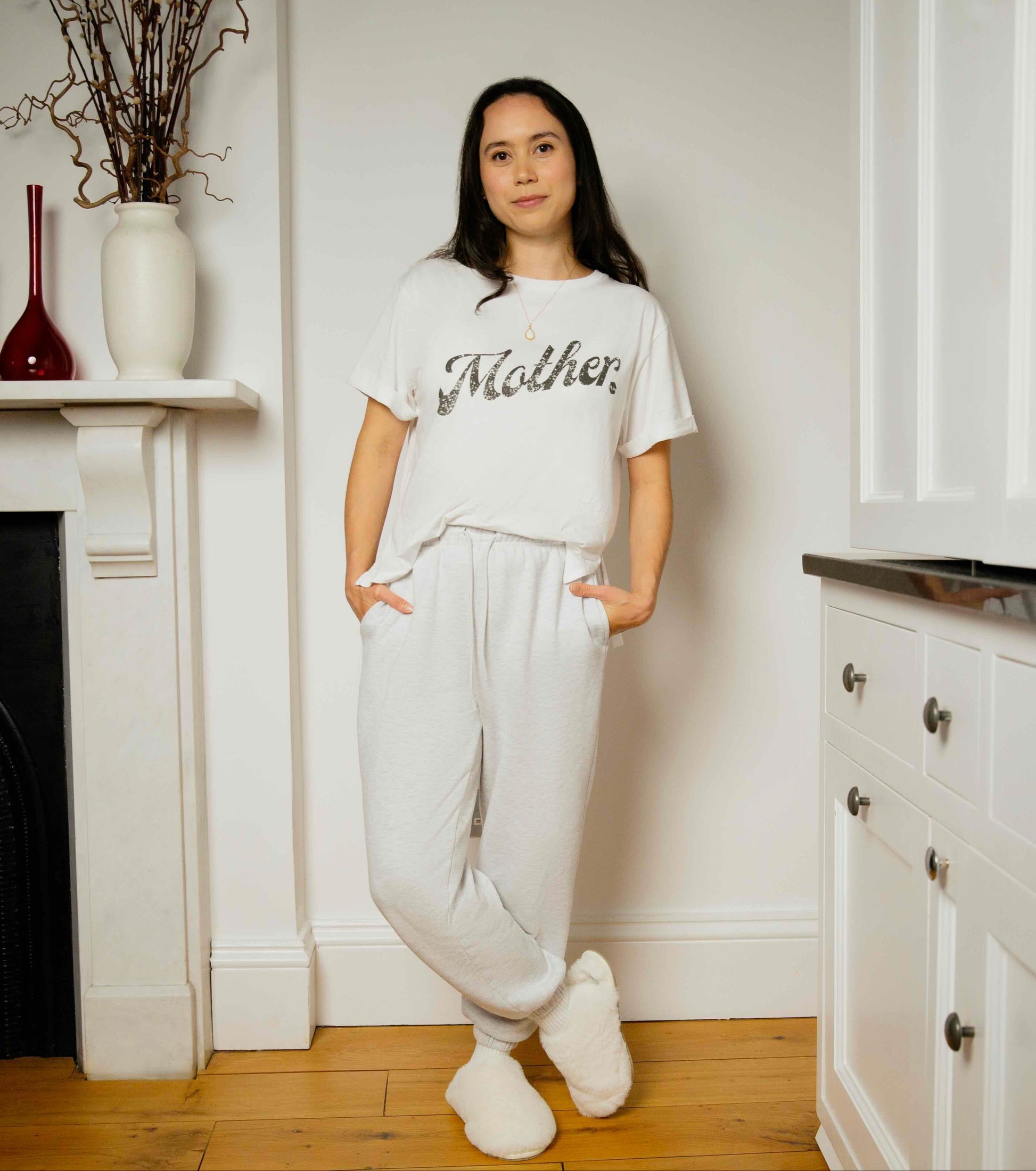 Woman wearing a white human milk 'Mother' t-shirt in a home.