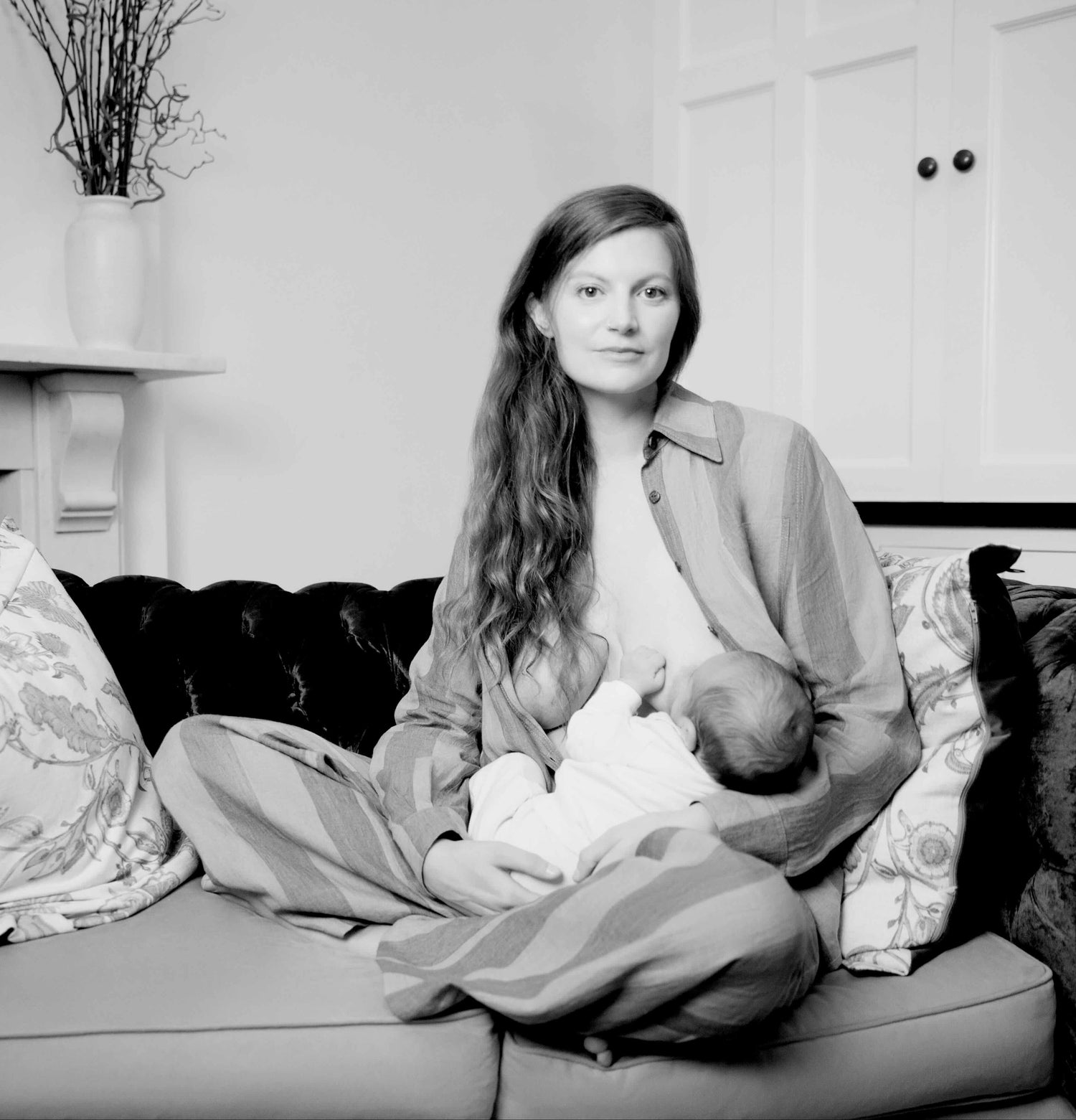 Woman breastfeeding a baby on a couch in a living room setting