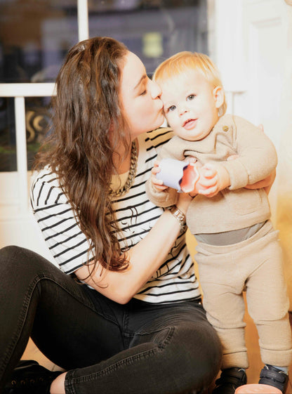 Woman wearing a Human Milk T-shirt kissing a baby on the cheek indoors