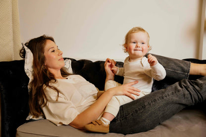 Woman wearing a human milk t-shirt and her child sitting on a couch together