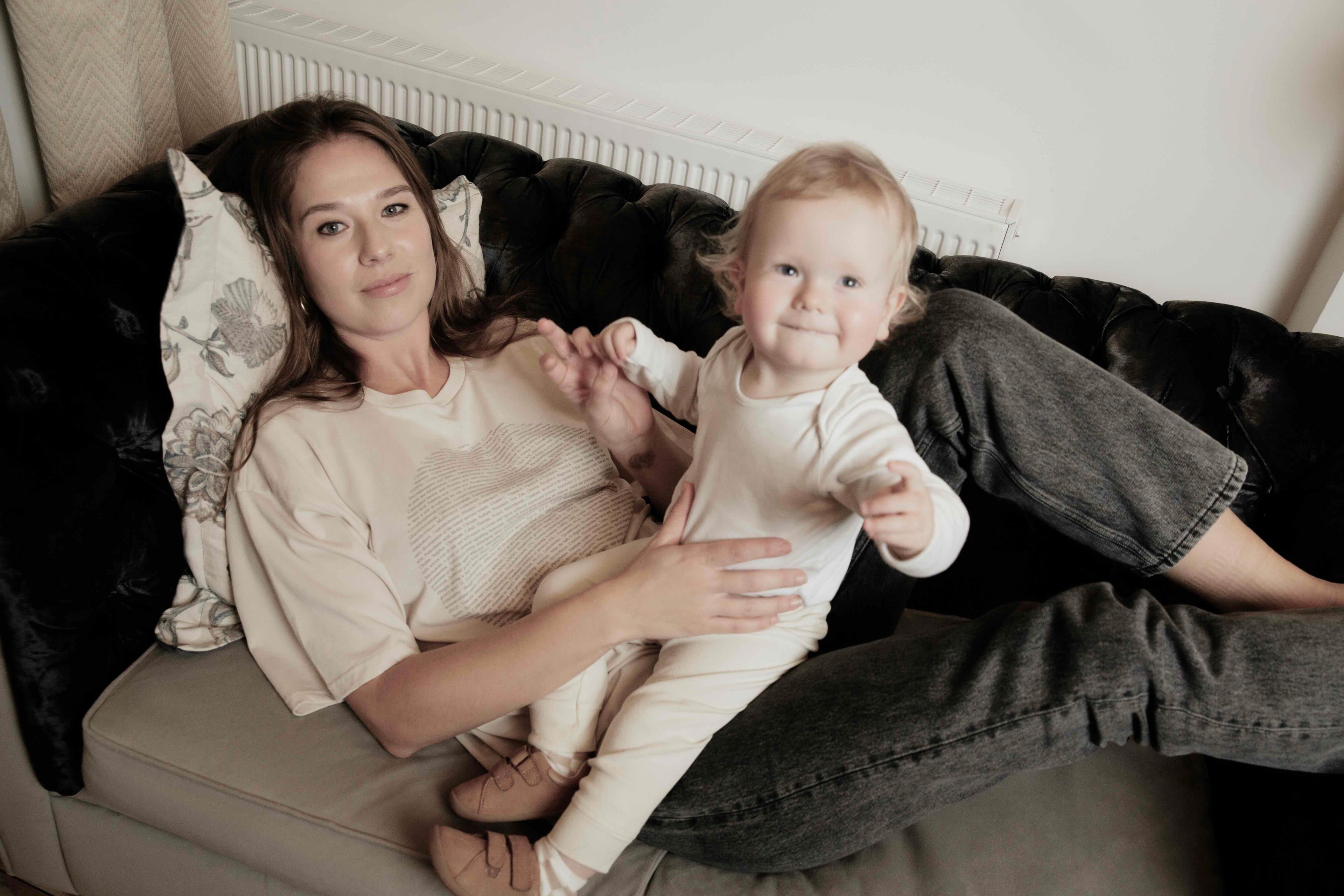 Woman wearing a human milk t-shirt holding her baby on a couch in a home setting