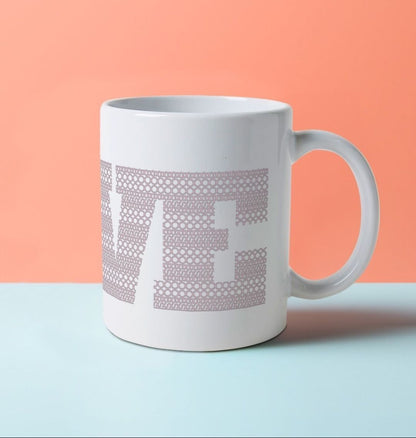 A white ceramic mug with the word LOVE on it, composed of a pattern made with the word BOOB.