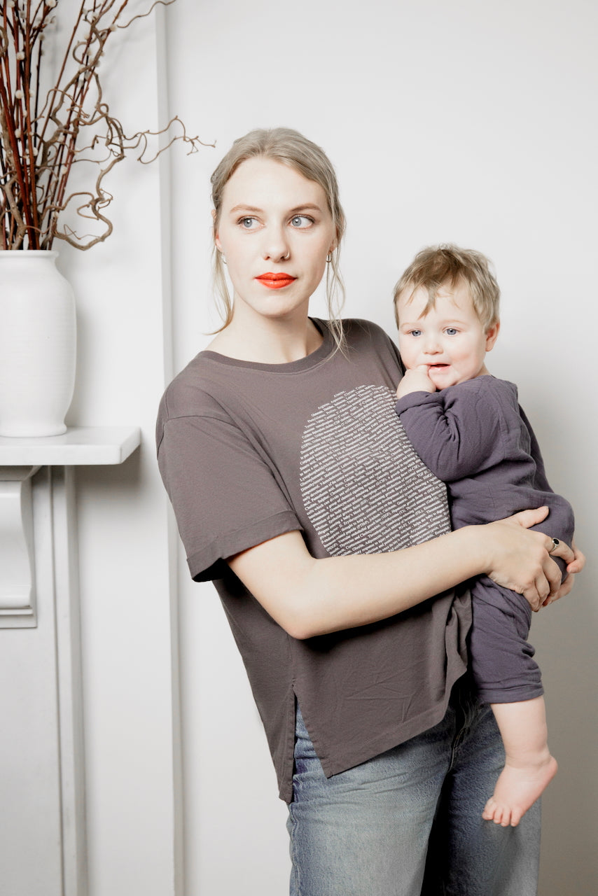 A mother carrying her baby boy, and wearing a human milk breastmilk moon t-shirt.