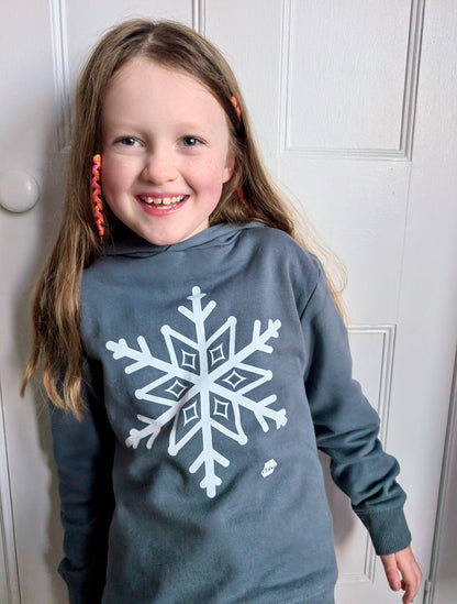 Young girl with long blonde hair wearing a human milk snowflake hoodie in blue