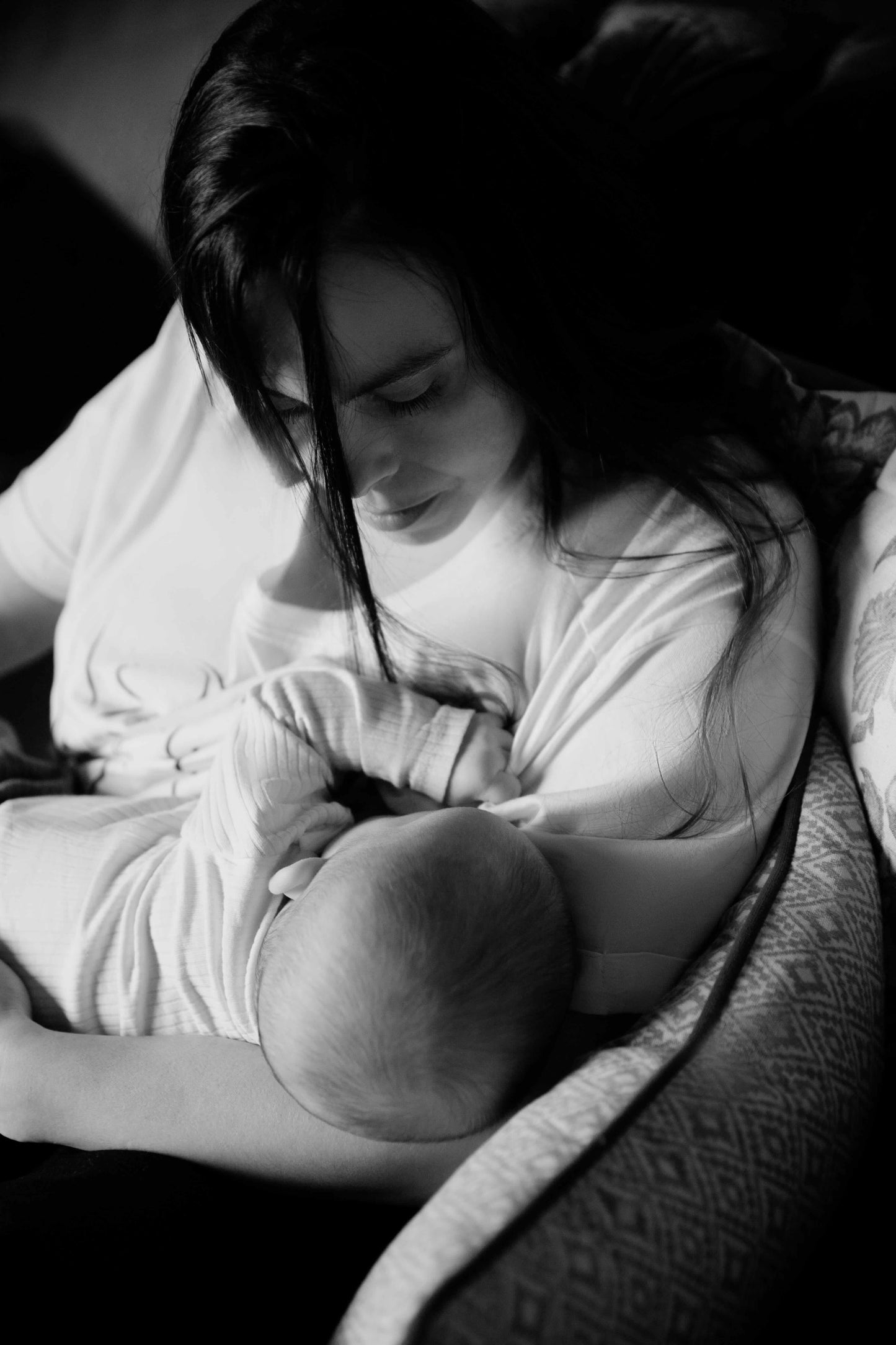 Black and white photo of a woman breastfeeding a baby, wearing a Human Milk T-shirt.